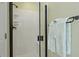 Close-up of a white tile and glass walk-in shower with black trim and a blue towel at 4204 Magnolia Ct, North Charleston, SC 29420