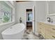Bright bathroom boasts a modern vanity, freestanding tub by a window and stylish herringbone tile floors at 4701 Apple St, North Charleston, SC 29405