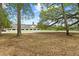 White horse barn surrounded by expansive acreage with mature trees and a carpet of fallen leaves at 5276 7Th Green Dr, Hollywood, SC 29449