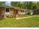 Charming brick home with a vibrant red door, complemented by flowering plants and a well-kept lawn at 6018 Ridgecrest Ave, Hanahan, SC 29410