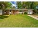 Charming brick home featuring lush landscaping, a well-manicured lawn, and an attached garage with driveway at 6018 Ridgecrest Ave, Hanahan, SC 29410