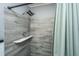 Close up of the shower with gray wood-look tiles and a marble corner shelf at 6018 Ridgecrest Ave, Hanahan, SC 29410