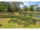 Expansive backyard boasts lush green lawn, fenced in fire pit area, and serene water views at 68 Oyster Point Row, Charleston, SC 29412