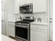 A kitchen featuring stainless steel stove and microwave, along with white cabinets and subway tile backsplash at 7483 Hawks Cir, Hanahan, SC 29410