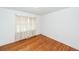 A minimalist bedroom featuring hardwood floors, white walls, and natural light from a window at 783 Dills Bluff Rd, Charleston, SC 29412