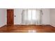 Sunlit living room showcasing refinished hardwood floors, a window with drapes, and a classic wood door at 783 Dills Bluff Rd, Charleston, SC 29412