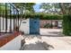 Photo of a blue gate framed by lush greenery and brick accents, offering a glimpse of a brick house beyond at 8 Poulnot Ln, Charleston, SC 29401