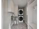 Efficient laundry room with stacked washer/dryer, utility sink, tile flooring, and built-in shelves at 8 Poulnot Ln, Charleston, SC 29401