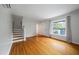 Bright living room with hardwood floors, stairs to the left, and a sun-filled window offering outdoor views at 8 Poulnot Ln, Charleston, SC 29401