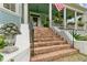 Brick steps leading up to the quaint front porch, framed by white columns, plants, and flags at 803 S Main St, Summerville, SC 29483