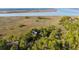 An aerial view showcases a home nestled within a lush landscape along the coast at 83 Blue Heron Pond Rd, Kiawah Island, SC 29455