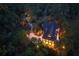 Aerial night view of an illuminated home with a pool nestled amongst the trees at 83 Blue Heron Pond Rd, Kiawah Island, SC 29455