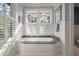 Serene bathroom featuring a soaking tub, marble countertop, wainscoting, and natural light at 83 Blue Heron Pond Rd, Kiawah Island, SC 29455
