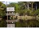 Scenic pond view with a covered wooden bridge amidst lush greenery and calm waters reflecting the structure at 83 Blue Heron Pond Rd, Kiawah Island, SC 29455