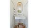 Stylish powder room featuring a unique sink, decorative mirror, and a woven basket at 9 Intracoastal Ct, Isle of Palms, SC 29451