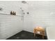 Modern shower with white subway tile, a dark tiled floor, and a wooden bench at 9 Intracoastal Ct, Isle of Palms, SC 29451