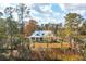 An exterior elevation of a 2-story white farmhouse with metal roof surrounded by mature trees at 116 Peninsula Dr, Ravenel, SC 29470