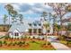 An exterior elevation of a 2-story white farmhouse with metal roof, manicured lawn, and mature trees at 116 Peninsula Dr, Ravenel, SC 29470