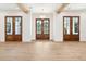 Spacious foyer with blonde wood flooring, white walls, wood ceiling beams, and three sets of glass doors at 116 Peninsula Dr, Ravenel, SC 29470
