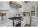 Close-up of kitchen featuring stainless steel range, marble countertops, white cabinets, and stylish backsplash at 123 Hyacinth St, Summerville, SC 29483