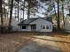 Quaint single-story home with a driveway, blue shutters, and mature trees on a sun-drenched lot at 143 Mickler Dr, Ladson, SC 29456
