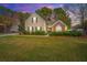 Charming two-story home featuring brick accents and a beautifully landscaped front yard at twilight at 177 Thousand Oaks Cir, Goose Creek, SC 29445