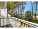 Balcony with a wooden deck and white railing overlooking tall trees and a blue sky at 2 Townpark Ln # D, Charleston, SC 29412