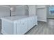 Modern kitchen island with white cabinets, light countertops, and gray wood flooring at 203 Bilge Rd, Ridgeville, SC 29472