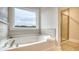 Bathroom featuring a soaking tub with neutral tile surround, window, and a glass enclosed shower at 210 Bilge Rd, Ridgeville, SC 29472