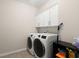 Functional laundry room with modern washer and dryer, overhead cabinets, and tiled flooring at 215 Center Hill Ct, Summerville, SC 29485