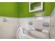Small bathroom with tiled wall, toilet, and sink, in a bright green room at 3143 Bonanza Rd, Charleston, SC 29414