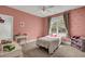 Charming pink bedroom with a window view and comfortable furnishings, including a bed, desk, and toy storage at 3302 Porchview Pl, Johns Island, SC 29455