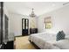 Sun-filled bedroom with a queen bed, yellow rug, and an elegant chandelier and natural light from the window at 478 Huger St, Charleston, SC 29403