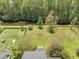 Aerial view of the property showcasing a spacious, fenced backyard, a fire pit, lush greenery, and proximity to a tranquil stream at 529 Beverly Dr, Summerville, SC 29485