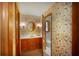 A full bathroom showcases floral wallpaper, wood cabinets, vanity, and a round mirror above the sink at 643 Edmonds Dr, Charleston, SC 29412
