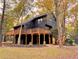 Striking dark home exterior featuring an expansive wraparound deck and fall foliage at 6464 St Anthony Dr, Hollywood, SC 29449