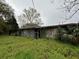 Overgrown backyard view of a weathered single story home needing repair at 75 Rentz St, Varnville, SC 29944