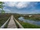 Scenic marsh view with a wooden walkway leading towards distant homes under a partly cloudy sky at 755 Jumbo Ln, Edisto Island, SC 29438