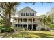 Beautiful two-story home with a classic white exterior, black shutters, and an inviting porch perfect for relaxing at 825 Marsh Grove Ave, Mount Pleasant, SC 29464