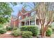 Side view of a red brick house featuring a covered front porch, mature trees, and lush landscaping at 1185 Out Of Bounds Dr, Summerville, SC 29485