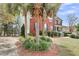 Side view of a brick home featuring mature landscaping, palm trees, and a charming front porch at 1185 Out Of Bounds Dr, Summerville, SC 29485