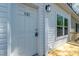 Close-up of a welcoming white front door, sidelight windows, and a neat porch, exuding curb appeal at 121 Dotson St, Harleyville, SC 29448
