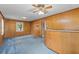Inviting living room with wood paneling, blue carpet, and a vintage ceiling fan, bathed in natural light at 1215 Redeemer Dr, Hanahan, SC 29410