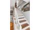 Classic staircase featuring hardwood steps, white railings, and decorative artwork, creating an elegant and inviting transition between floors at 15 N Adgers Wharf, Charleston, SC 29401