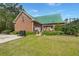 Charming brick home with a green metal roof, lush landscaping, and a welcoming pergola-covered patio at 1694 Jedburg Rd, Summerville, SC 29486
