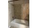 Bathroom shower with tan tiled walls, a shower head, white tub, decorative accent tiles, and tile floors at 233 N Pandora Dr, Goose Creek, SC 29445