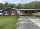 A charming single-story home with a brick facade and a convenient covered carport, surrounded by a green lawn and trees at 233 N Pandora Dr, Goose Creek, SC 29445