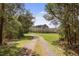 Gravel driveway curves through a lush forest setting, enhancing the privacy and natural beauty of the property at 2480 Royal Oak Dr, Johns Island, SC 29455