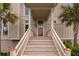Front entrance of the home features wooden stairs, beige siding, a brown door, and tropical palm trees at 2480 Royal Oak Dr, Johns Island, SC 29455