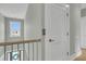 A hallway featuring hardwood floors, a white paneled door, a staircase, and a sunlit window at 2504 Ballast Pt, Mount Pleasant, SC 29466
